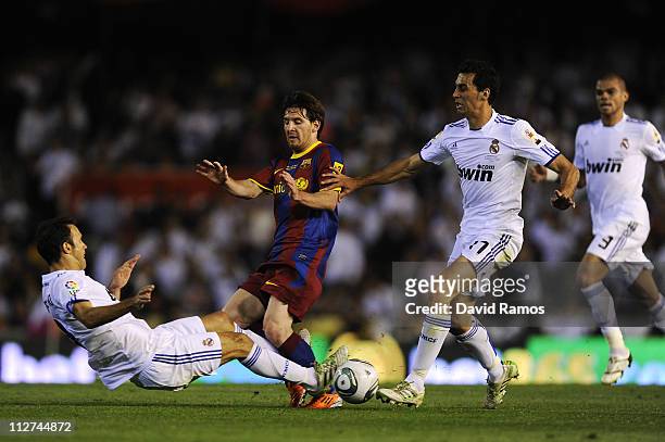Lionel Messi of FC Barcelona is tackled by Ricardo Carvalho and Alvaro Arbeloa of Real Madrid during the Copa del Rey Final between Real Madrid and...