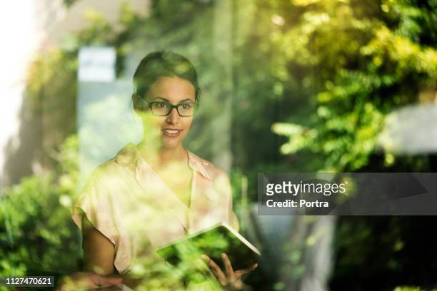 thoughtful businesswoman seen through window - cor verde imagens e fotografias de stock