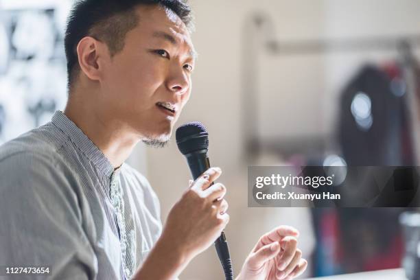 young businessman is speaking with a microphone - homme micro photos et images de collection