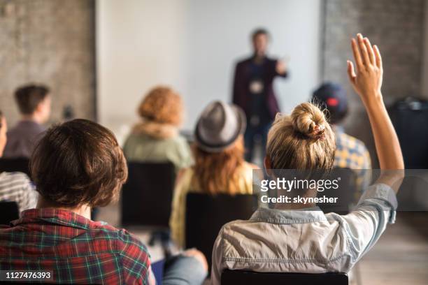 back view of a woman raising her hand on a seminar. - q and a stock pictures, royalty-free photos & images