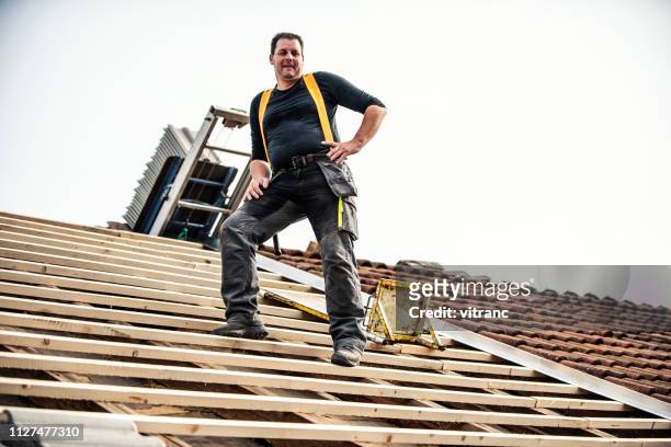 roofer che sostituisce le vecchie piastrelle - costruttore di tetti foto e immagini stock