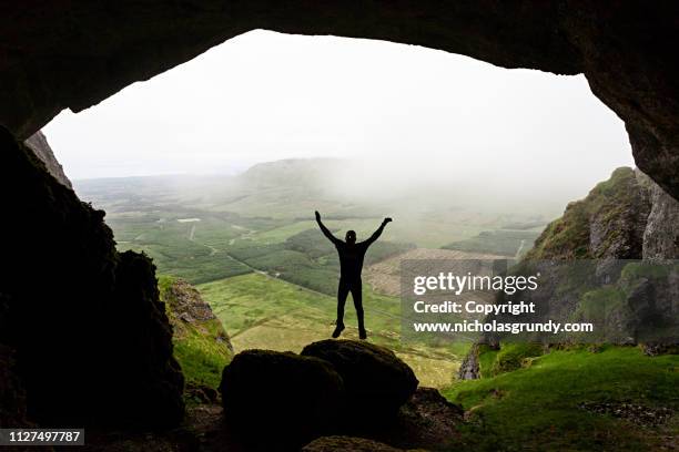hiker does star jump inside cave in ireland - star jump stock pictures, royalty-free photos & images