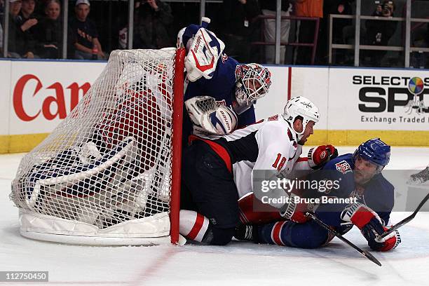 Goalie Henrik Lundqvist of the New York Rangers is pushed into the net by Marco Sturm of the Washington Capitals and Michael Sauer of the Rangers in...