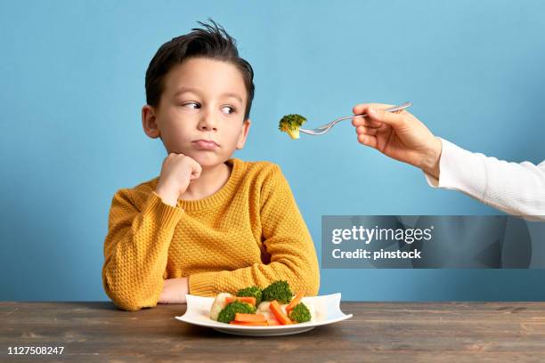 niño está muy contento con tener que comer verduras. - quejándose fotografías e imágenes de stock