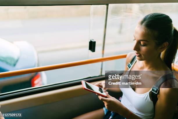woman traveling in bus texting - women phone city facebook tourist stock pictures, royalty-free photos & images