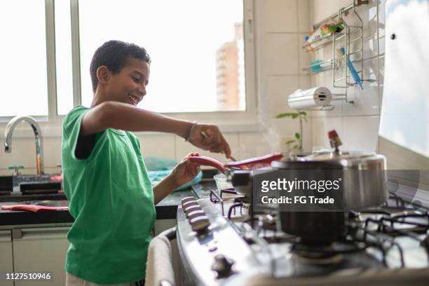 afro latino child cooking at home - boy cooking stock pictures, royalty-free photos & images