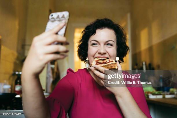 woman taking selfie while eating breakfast - essen mund benutzen stock-fotos und bilder