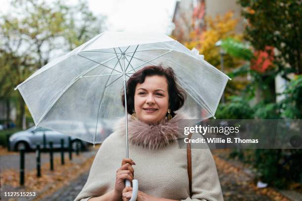 woman walking down street with umbrella - wandelschoenen stock-fotos und bilder