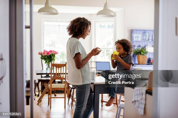 mutter benutzt smartphone, während sohn milch trinkt - mom sits on sons lap stock-fotos und bilder