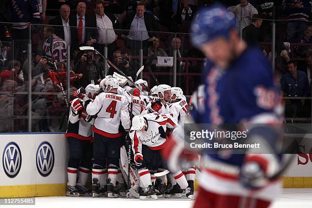 The Washington Capitals celebrate their 4-3 double overtime win as Bryan McCabe of the New York Rangers skates dejected in the foregroun in Game Four...