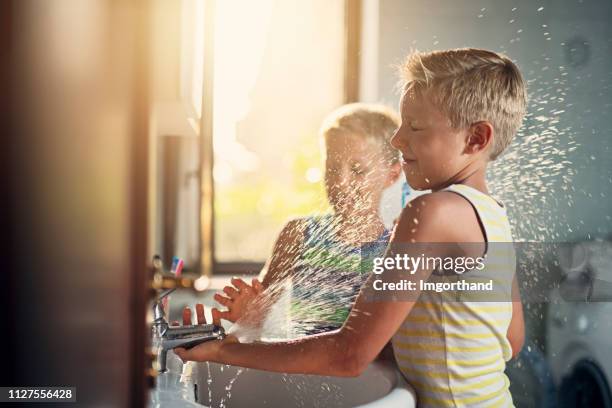 kleine jungen, die hände zu waschen und mit wasser spielen - water sprayer stock-fotos und bilder