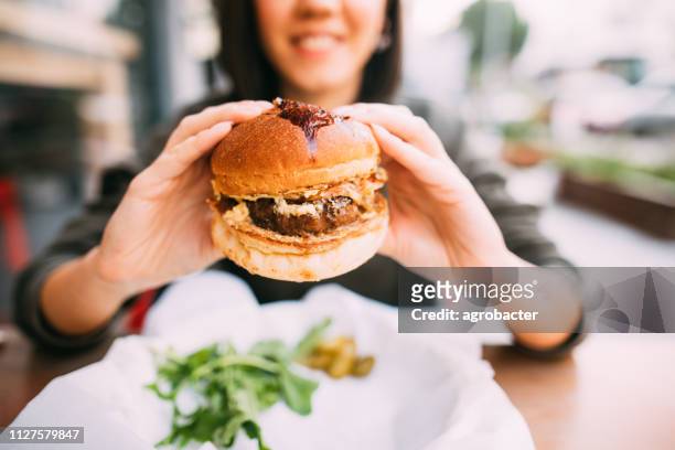 donna che mangia hamburger di manzo - adults eating hamburgers foto e immagini stock