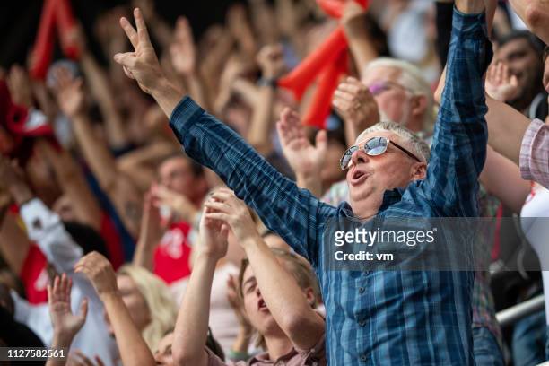 mann mit einem stadion-publikum erhobenen armen - fan stock-fotos und bilder