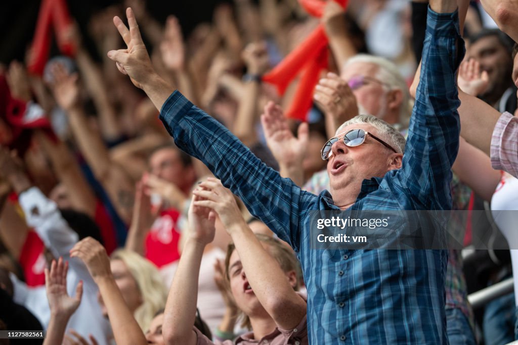 Man with arms raised in a stadium crowd