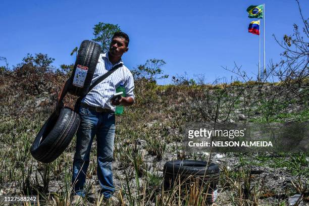 Venezuelan man carrying tyres rests as he cross the Brazil-Venezuela border from Pacaraima, Roraima State, Brazil, into Venezuela, on February 26,...