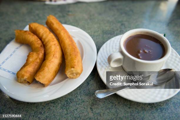 sticks of churros served with hot chocolate for dipping - churro stockfoto's en -beelden