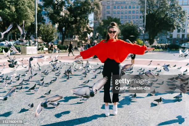 girl in barcelona jumping among the pigeons - spread joy stock pictures, royalty-free photos & images