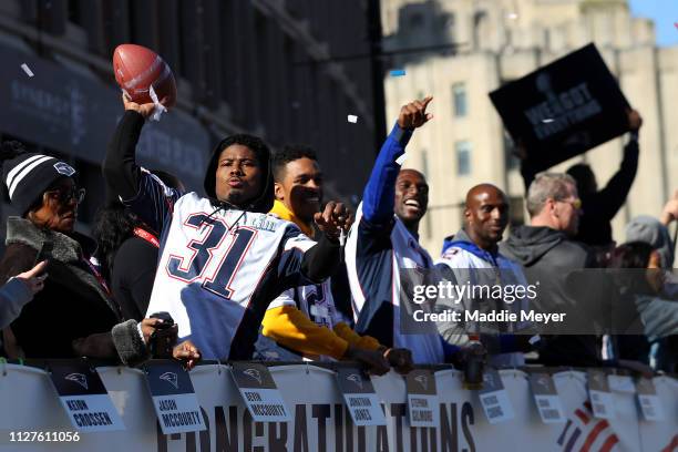 Jonathan Jones of the New England Patriots throws a football to fans on Cambridge street during the New England Patriots Victory Parade on February...