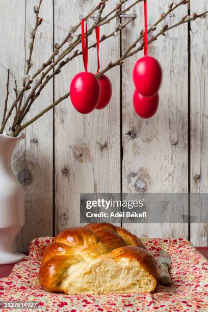 a plaited loaf of bread on a floral-patterned cloth with easter decoration - easter challah stock pictures, royalty-free photos & images