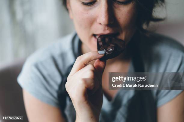 woman eating chocolate - chocolat noir photos et images de collection