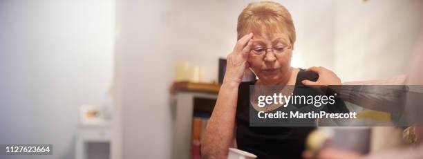 eine verärgert senior frau getröstet von einem freund - family on couch with mugs stock-fotos und bilder