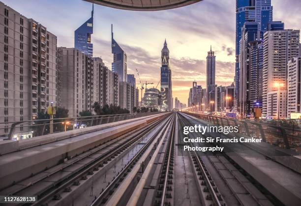 futuristic dubai skyline illuminated at dusk with driverless metro tracks on foreground, uae - dubai metro stock pictures, royalty-free photos & images