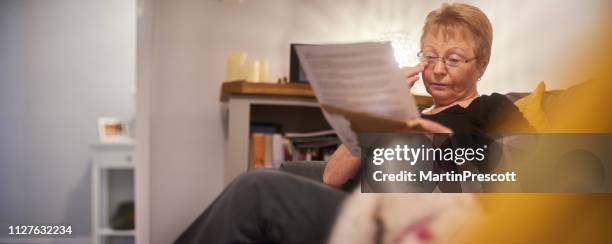 emotionele senior vrouw huilen als ze leest de brief - electricity bill stockfoto's en -beelden