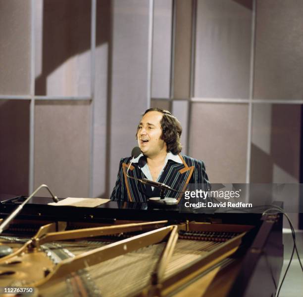 Neil Sedaka, U.S. Singer-songwriter and pianist, playing the piano and singing into a microphone during a live concert performance, circa 1973.