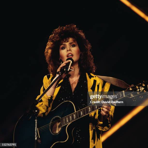 Marie Osmond, U.S.singer and musician, playing a guitar and singing into a microphone during a live concert performance, on stage at the Country...