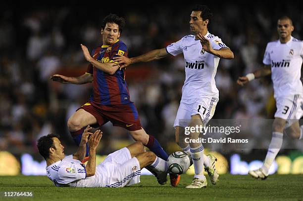 Lionel Messi of FC Barcelona holds a challenge by Carvalho and Arbeloa of Real Madrid during the Copa del Rey Final between Real Madrid and Barcelona...