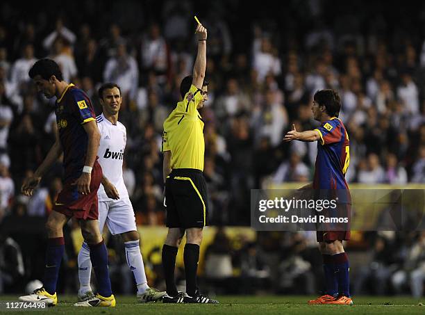 Referee Alberto Undiano Mallenco shows the yellow card to Lionel Messi of Barcelona during the Copa del Rey Final between Real Madrid and Barcelona...