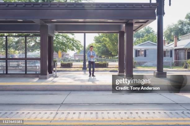 young man with digital tablet standing on commuter train platform - space station stockfoto's en -beelden