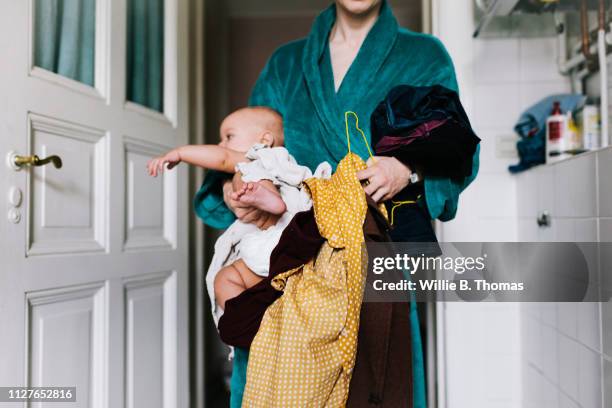 single mother with baby trying to get dressed - surchargé de travail photos et images de collection