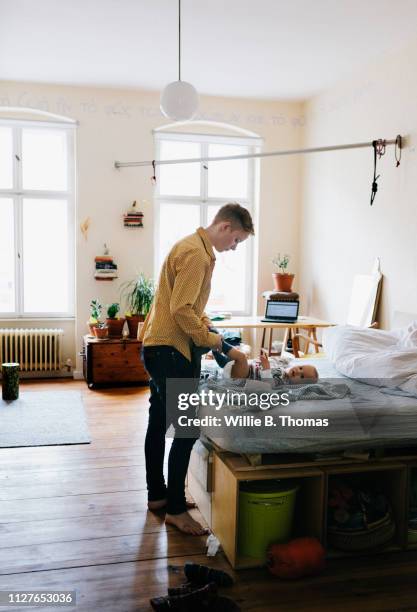single mother dressing her baby in bedroom - nappy stock pictures, royalty-free photos & images