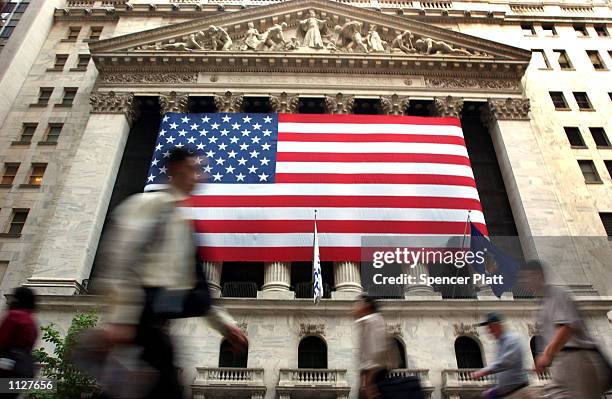 Pedestrians walk past the New York Stock Exchange July 16, 2002 in New York City. The Dow closed down in seven straight losing sessions, falling more...
