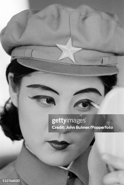 Young performer in uniform applying stage make-up, North Korea, February 1973.