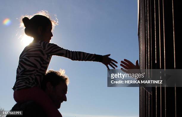 Girl from Anapra, a neighbourhood on the outskirts of Ciudad Juarez in Mexico, touches hands with a person on the United States through the border...
