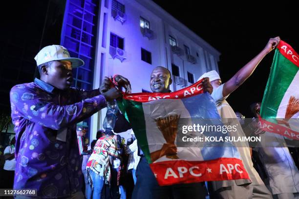 Supporters of the ruling All Progressives Congress celebrate with party flags in Abuja, Nigeria, after candidate President Mohammadu Buhari was...