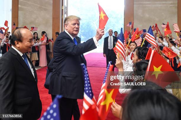 President Donald Trump waves a Vietnamese flag as Vietnam's Prime Minister Nguyen Xuan Phuc looks on upon his arrival for a meeting at the Government...