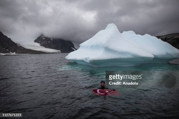 Sahika Ercumen, an internationally renowned Turkish diver, holds a flag of Turkey as she swims near an iceberg during her free-diving, marking the...