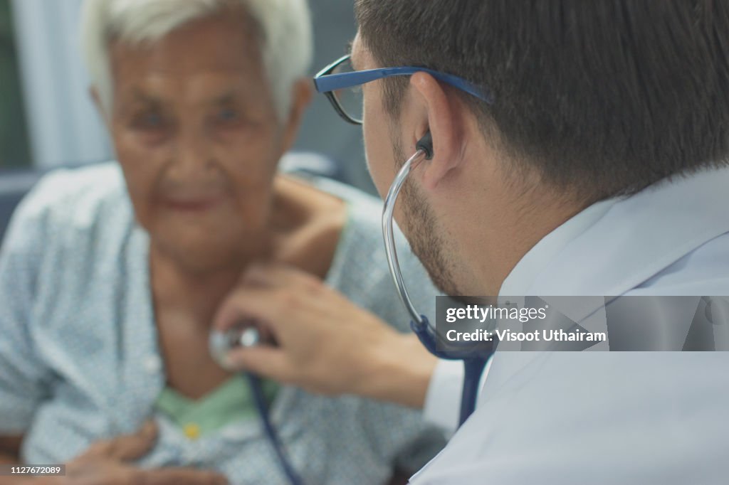 Young doctor listening heartbeat with stethoscope of old woman,Rural medicine concept.