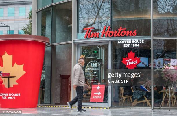 Man walks past Canadian coffee-and-donut shop Tim Hortons in Shanghai on February 27, 2019. - Tim Hortons opened it's first store in China on...