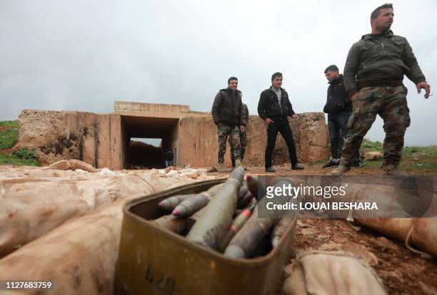 Syrian soldiers stand next to ammunition and packs they say are of C-4 explosives that were found in the southern province of Daraa on February 27...