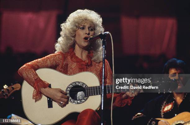 Tammy Wynette , U.S. Country music singer-songwriter, singing into a microphone and playing the guitar during a live concert performance at the...