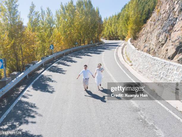 groom and bride happy running on the road - bride running stock pictures, royalty-free photos & images