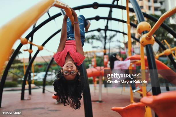 girl upside down on the jungle gym - child park stockfoto's en -beelden