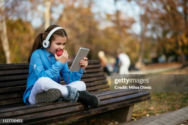girl using digital tablet at a park - using tablet screen stock pictures, royalty-free photos & images