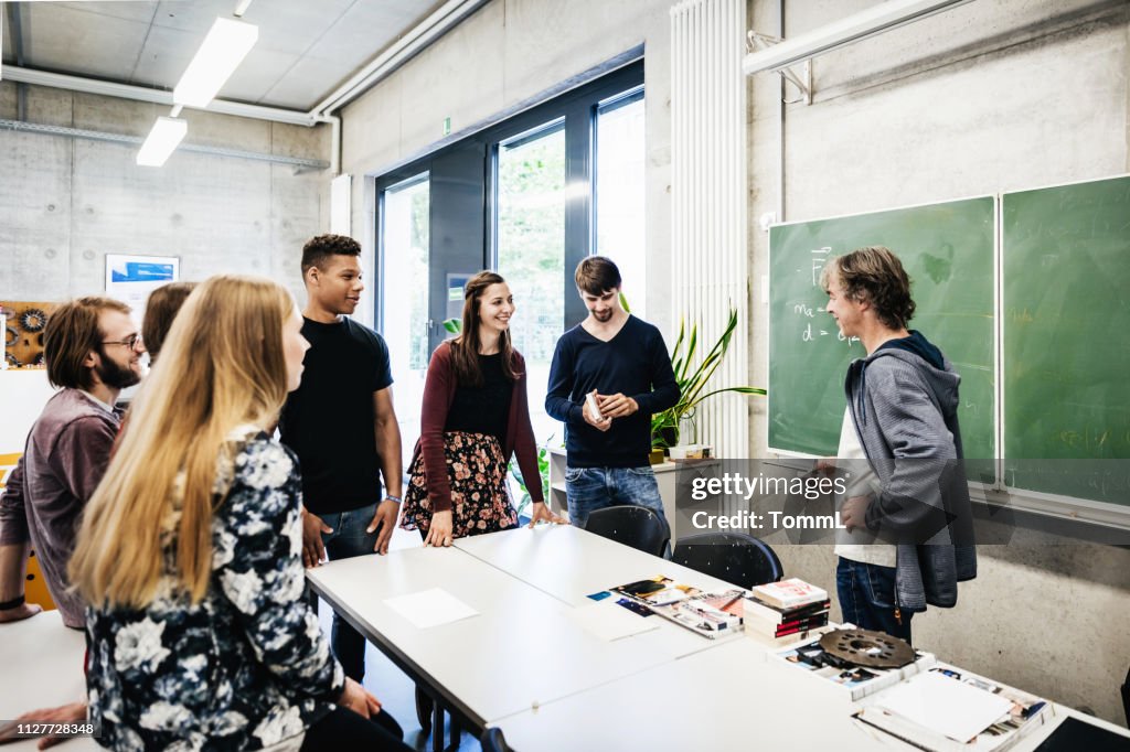 University Tutor Talking With Students In Front Of Blackbaord