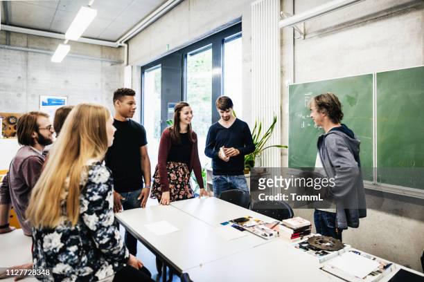 university tutor talking with students in front of blackbaord - adult student stock pictures, royalty-free photos & images