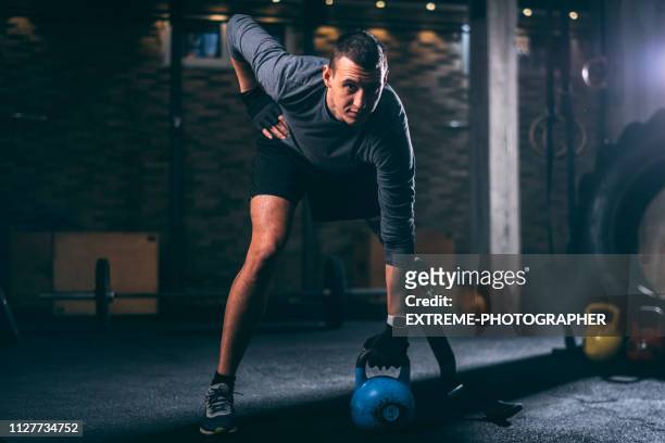 young handicapped athlete with a prosthetic leg doing a one arm kettlebell swing exercise in a gym gym - human limb stock pictures, royalty-free photos & images